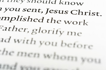 A macro shot of a page portion of a biblical text with selective focus on the word "Jesus Christ."