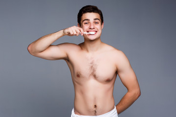 Young man brushing his teeth.  Man brushing teeth isolated on gray!