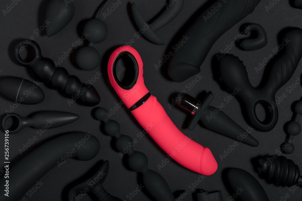 Wall mural erotic pleasure toys on a black background. sex gadgets and masturbation devices. pink dildo surroun