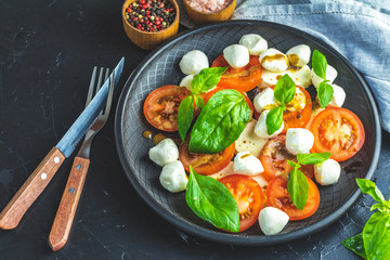 Italian caprese salad in black ceramic plate