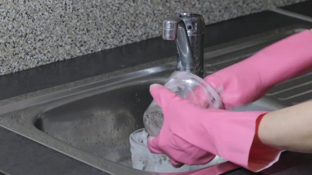 girl in rubber gloves washes dishes with foam