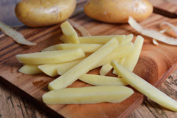 cut pieces fresh potato on wooden cutting board