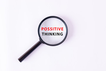 Motivation concept. An enlarged fragment of expression in the lens of a magnifying glass with text "POSSITIVE THINKING".