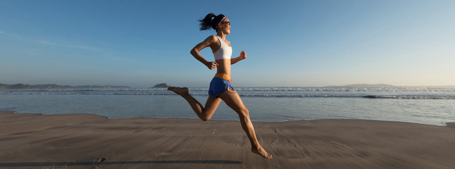 young fitness woman running at sunrise beach - Powered by Adobe