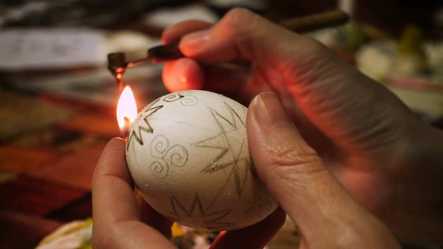 female craftman hands painting easter egg traditonal folk process creating layer by layer with the wax and using multicolored paints close up