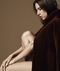 Young beautiful hipster girl sitting thinking  sexy in brown spring jacket naked on beige 