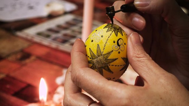 female craftman hands painting easter egg traditonal folk process creating layer by layer with the wax and using multicolored paints close up