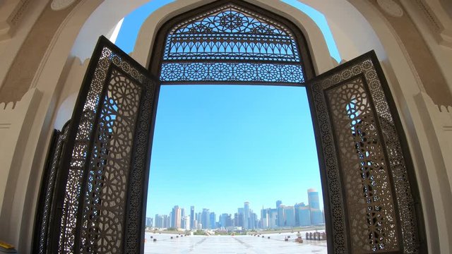 Modern skyscrapers of Doha West Bay skyline view from State Grand Mosque in Doha, Qatar, Middle East, Arabian Peninsula. Door of entrance at Mosque in Arabian style.