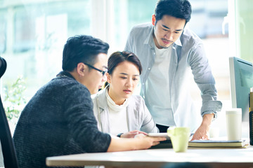 three young asian entrepreneurs discussing business in office