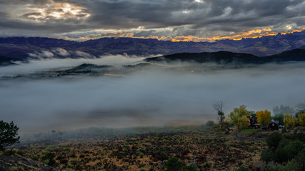 Rising sun outlining the ridge with autumn mist covering Ridgway Colorado