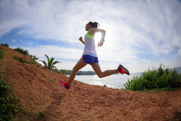 Woman trail runner running on seaside hills