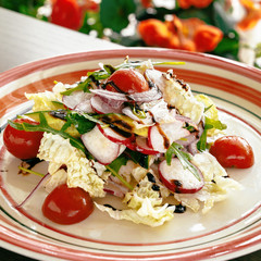 Spring fresh salad from radish, cabbage, avocado, tomatoes, arugula, potatoes, cucumbers. Sunlight from the window. Dish on a white plate. Close-up. Creative Cuisine.