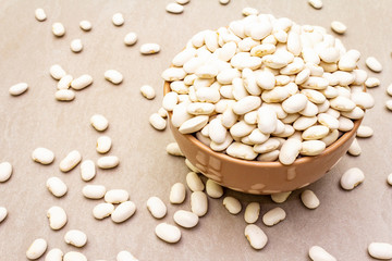 Dry lima beans in ceramic bowl on stone background, top view, wallpaper, close up.