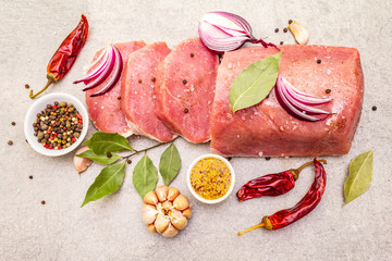 Raw pork tenderloin with vegetables and spices. Cooking meat background, fresh brisket boneless steak on stone background.