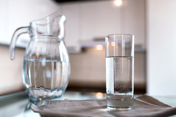 A glass of fresh water with crafin on the background of a modern kitchen.