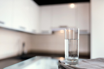 A glass of fresh water with crafin on the background of a modern kitchen.