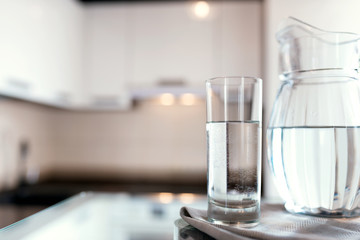 A glass of fresh water with crafin on the background of a modern kitchen.