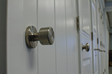 A low view of the round silver style handles along the wall of doors in the store. 