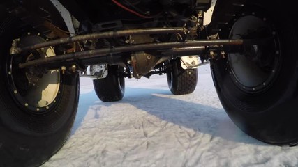 Gopro view from car bottom side. Swamp buggy is driving on snow and ice of frozen lake Hanka in Russia