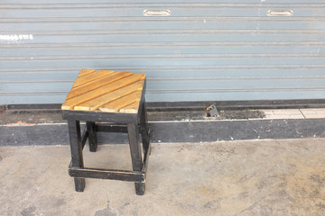 Wooden stool in front of metal door.