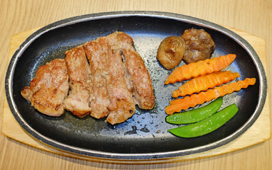 Top view of grilled beef steaks served with vegetables on wooden board