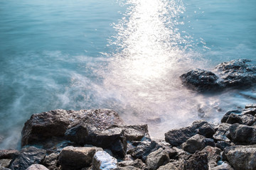 beautiful sea waves and the rocks with sunlight reflection, long exposure photography for smooth water