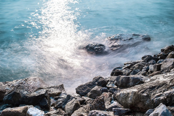 beautiful sea waves and the rocks with sunlight reflection, long exposure photography for smooth water