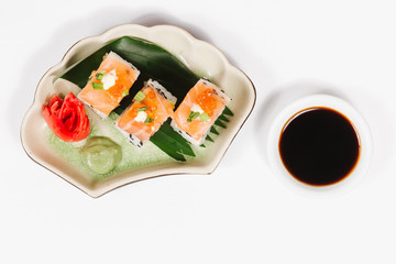 The concept of Japanese and Chinese cuisine. Sushi rolls laid out on a plate and soy sauce. On white background