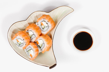 The concept of Japanese and Chinese cuisine. Sushi rolls laid out on a plate and soy sauce. On white background