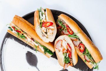 Traditional oriental cuisine of  Vietnam. Sandwiches with meat, tomatoes, chicken, hot pepper and greens on a plate