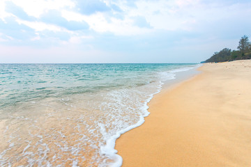 Clean sand on the beach have sea wave coming up diagonal to island, with soft blue sky with cloudy