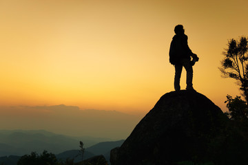 Silhouette traveler stand to watch the sunset on the mountain