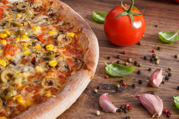 Vegetarian pizza and ingredients with spices on rustic board, fast food