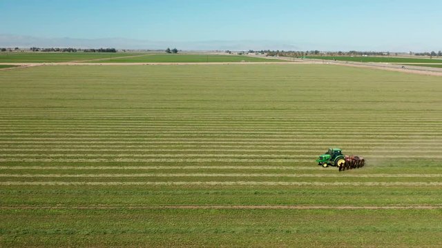 Aerial shot of tractor pulling harrows in Imperial, California