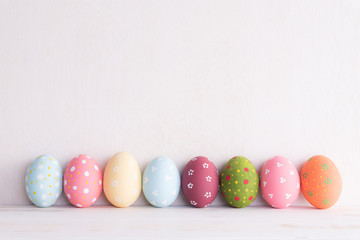 Happy easter! Row Easter eggs on bright white wooden background.