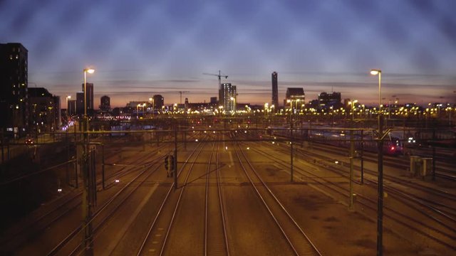 Overview of train tracks and Malmö, Sweden skyline during sunset.