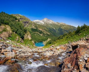 Large panorama, the river flows from the mountains into the lake. The Caucasus Mountains on a summer, clear day. Tourie Lake in the Outskirts of Dombai. .