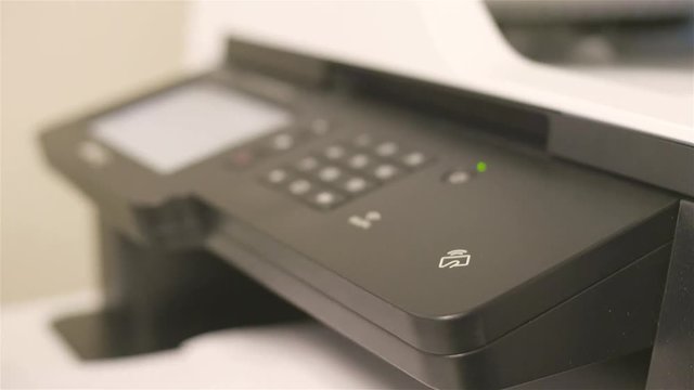Follow of hands pressing buttons on black printer 