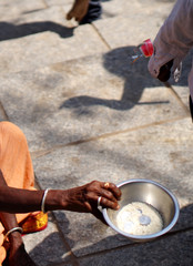Hand of poor Indian old or senior woman holding a plate and begging in front of a temple