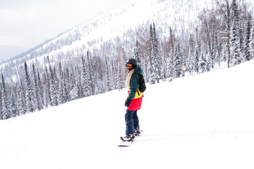 Fototapeta na wymiar Female snowboarder freerider rides a snowboard on a snowy slope.