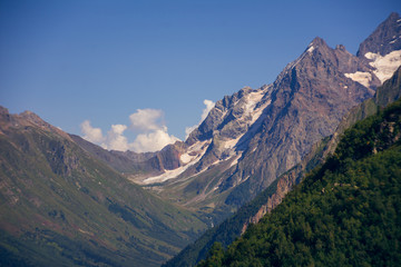 Fototapeta premium Peaks of mountains in the neighborhood of Dombai. Caucasus Mountains summer, clear day from the forest.