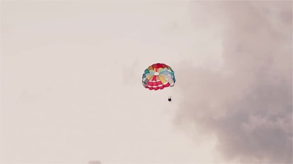 Parasailing in evening. Bright parachute on a background of a sky.