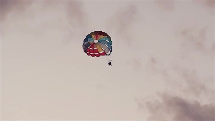 Parasailing in evening. Bright parachute on a background of a sky.