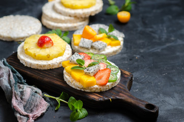 Multigrain rice cakes sandwich with berries, fruit and cream cheese for healthy breakfast.
