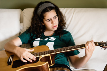 Girl practicing chords on acoustic guitar