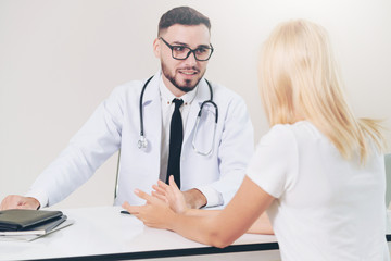 Male doctor is talking to female patient in hospital office. Healthcare and medical service.
