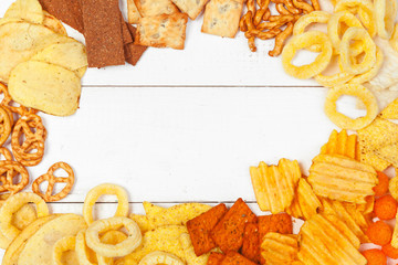 Mix of snacks : pretzels , crackers , chips  and nachos on the table