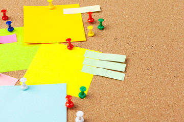 Cork board with several colorful blank notes with pins