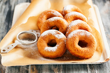 Homemade donuts  with powdered sugar on a wooden baclground