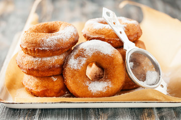 Homemade donuts  with powdered sugar on a wooden baclground